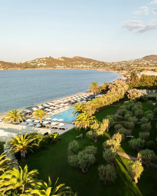 Vue aérienne d'une plage bordée de transats et d'une piscine au sein d'un complexe hôtelier.