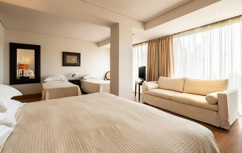 Chambre lumineuse avec lits jumeaux et coin salon.