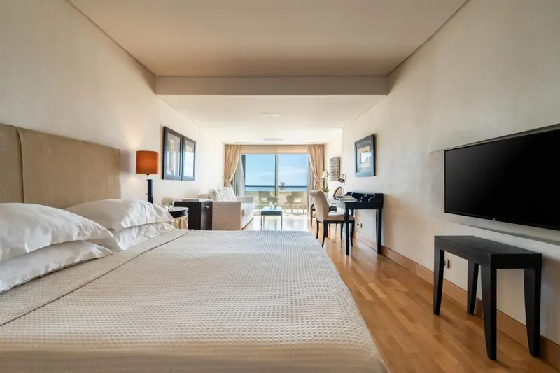 Une chambre lumineuse avec un grand lit et un canapé près d'une fenêtre.
