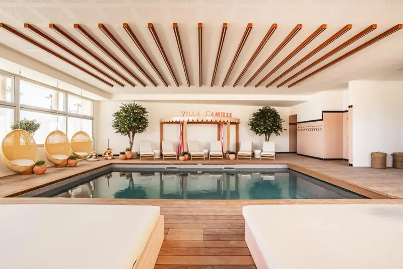 Piscine intérieure lumineuse avec mobilier de détente.
