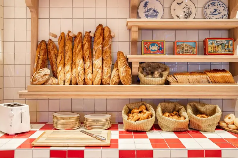 Des baguettes et des viennoiseries sont exposées sur des étagères en bois.