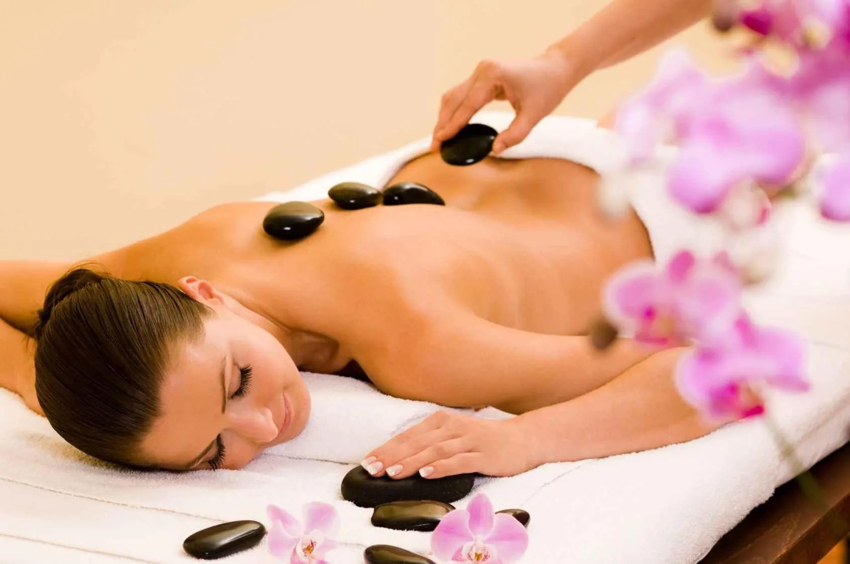 Une femme allongée reçoit un massage aux pierres chaudes sur une table.