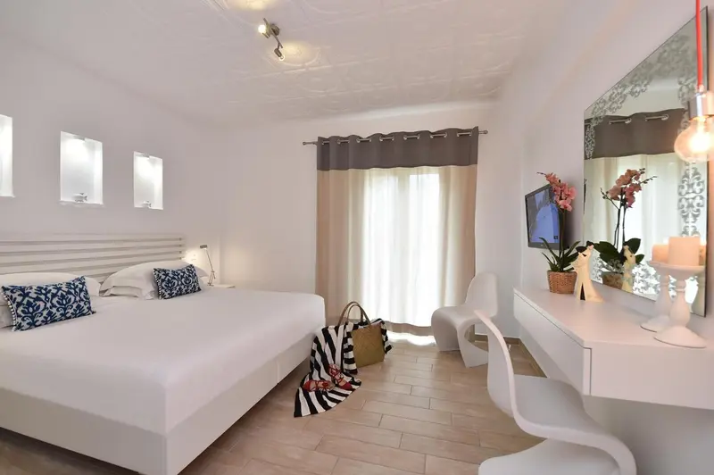 Chambre lumineuse avec un grand lit et un espace coiffeuse.