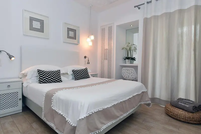 Une chambre lumineuse avec un grand lit recouvert d'une courtepointe et de coussins.
