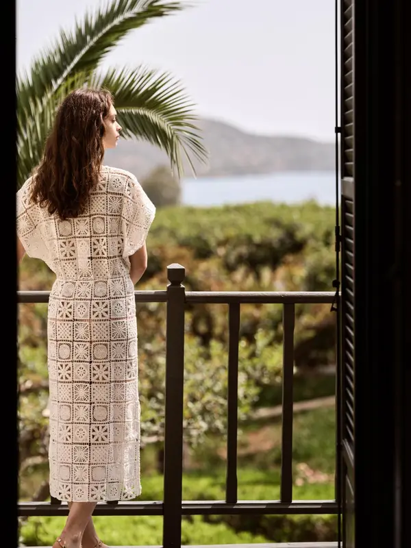 Une femme se tient sur une terrasse en admirant la vue sur la mer.