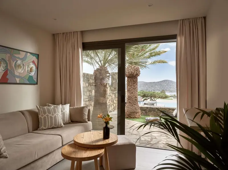 Un salon lumineux s'ouvre sur une terrasse avec vue sur une végétation luxuriante et une piscine.