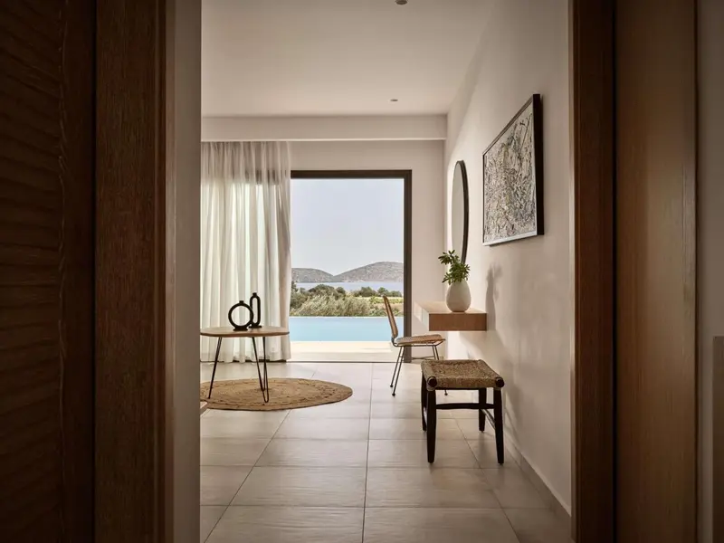 Une chambre lumineuse s'ouvre sur une vue dégagée sur la mer et une piscine.