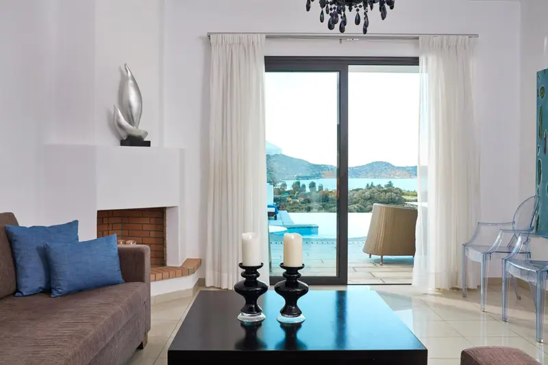 Un salon lumineux s'ouvre sur une vue dégagée sur la mer et une piscine.