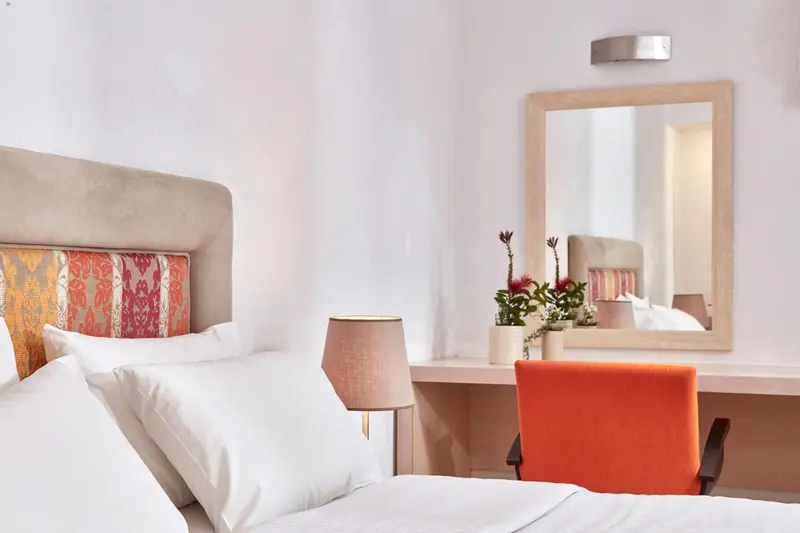 Une chambre lumineuse avec un lit fait et un bureau.
