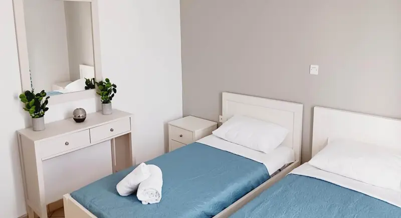 Une chambre lumineuse avec deux lits simples et une commode.