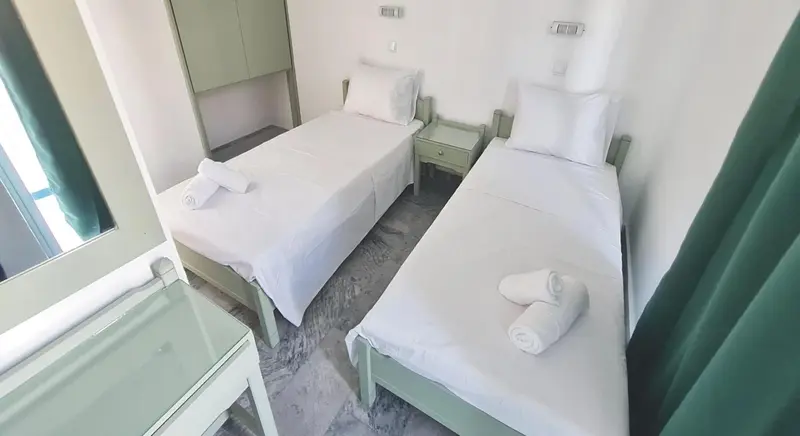 Une chambre avec deux lits simples et une table de chevet.