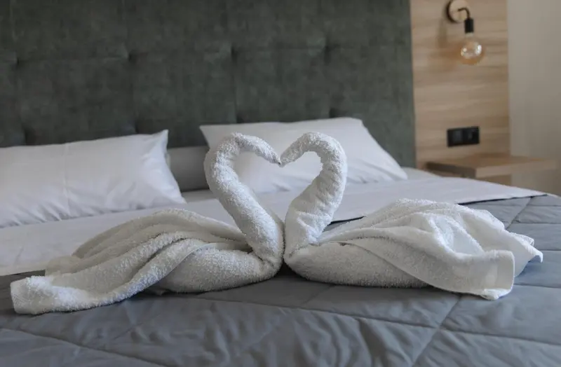 Un lit double est soigneusement fait avec des serviettes en forme de cygnes.