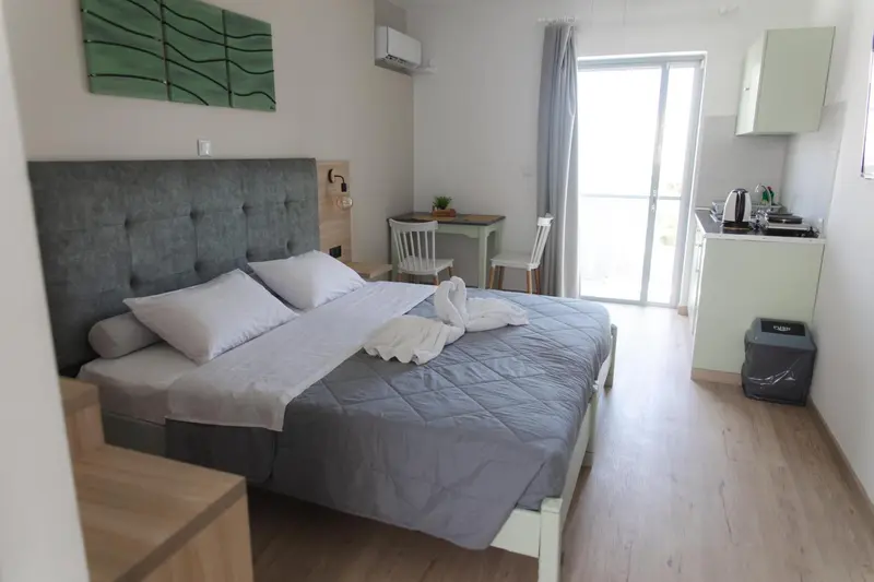 Une chambre lumineuse avec un lit fait et un espace cuisine.