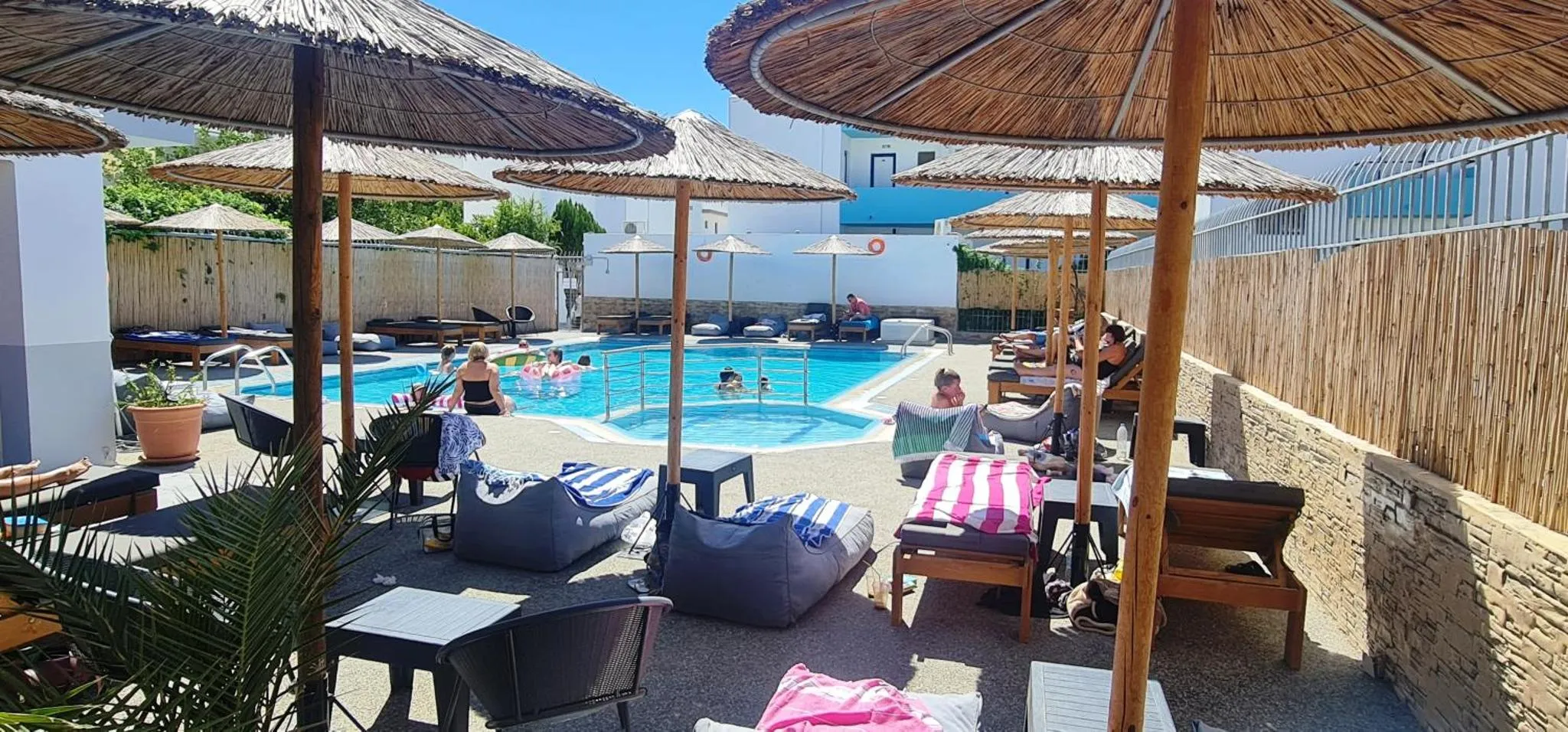 Transats et parasols ombragent une piscine rectangulaire entourée d'une terrasse.