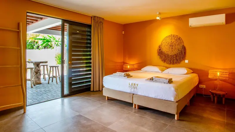 Une chambre lumineuse avec un grand lit et une terrasse accessible par une baie vitrée.