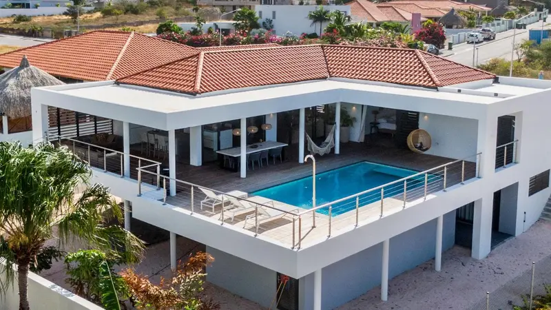 Vue aérienne d'une villa blanche avec piscine et terrasse aménagée.