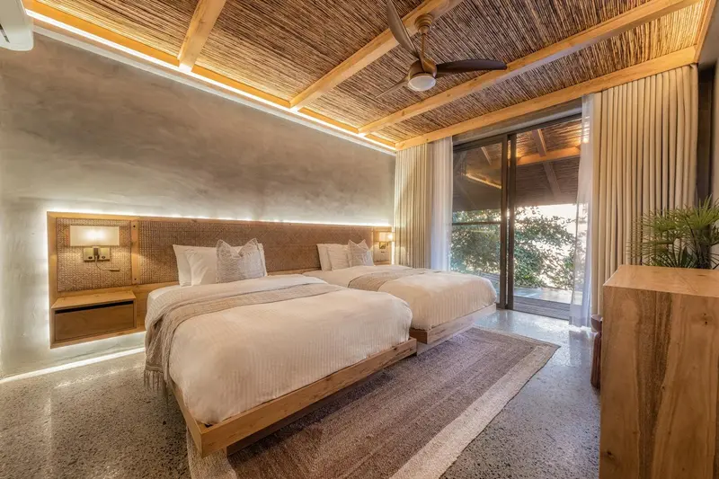 Chambre lumineuse avec deux lits simples et décoration naturelle.