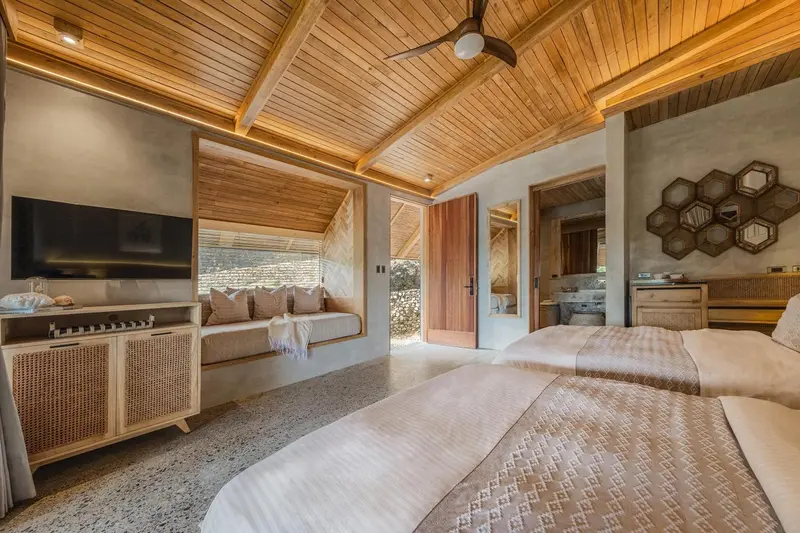 Une chambre lumineuse avec deux lits et un coin salon intégré.