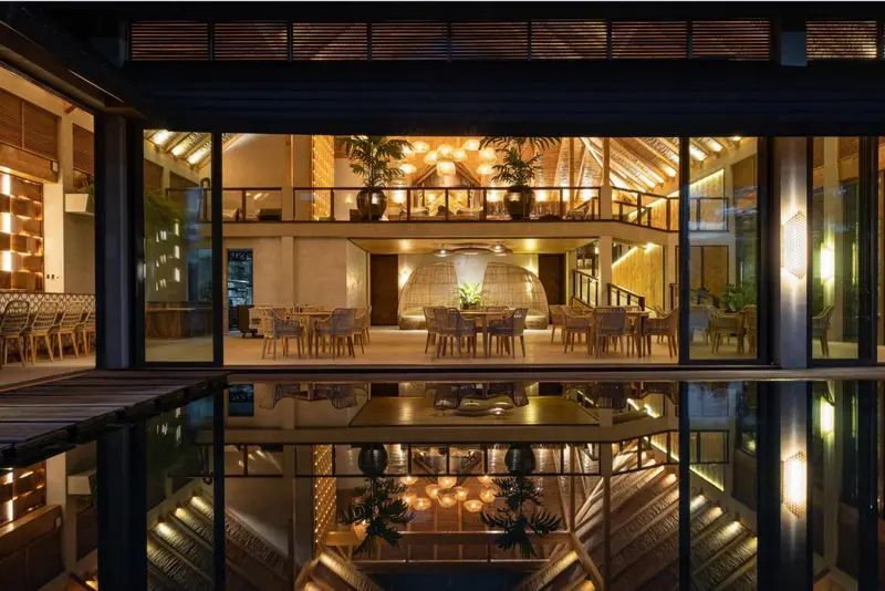 Une salle à manger lumineuse s'ouvre sur une terrasse avec des reflets dans une piscine.