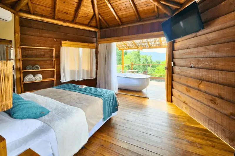 Une chambre lumineuse avec un lit fait et une baignoire sur une terrasse.