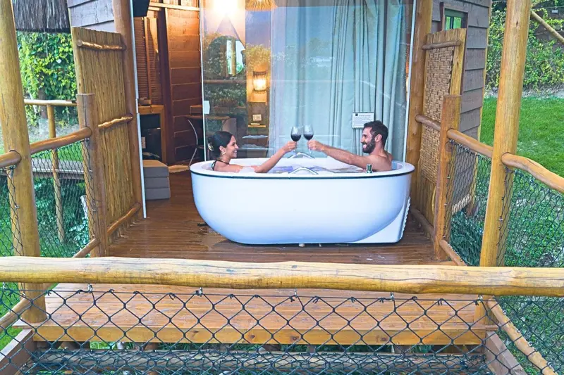 Un couple trinque dans un bain à remous sur une terrasse en bois.