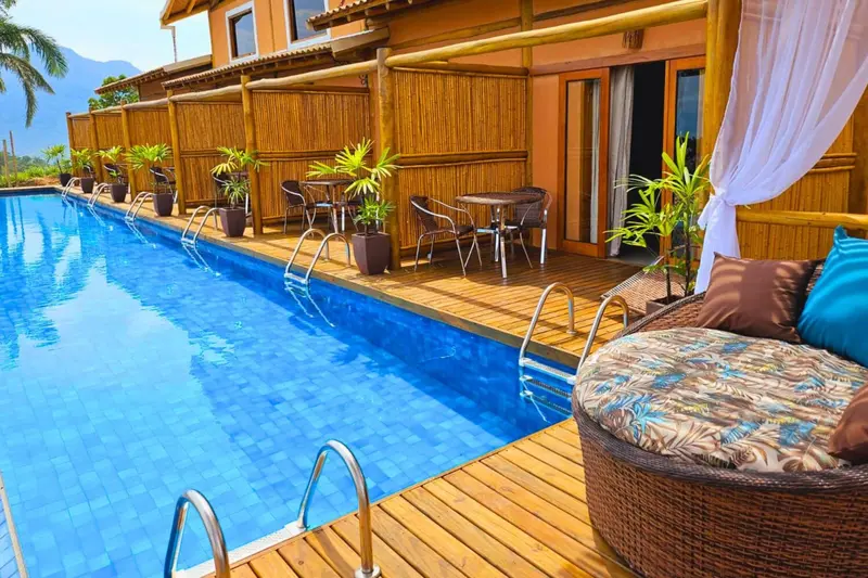 Terrasse en bois avec mobilier de détente donnant sur une piscine bleue.