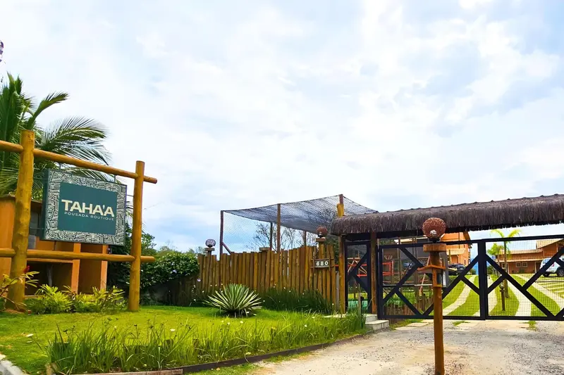 Entree d'un etablissement avec une signalisation et une vegetation tropicale.