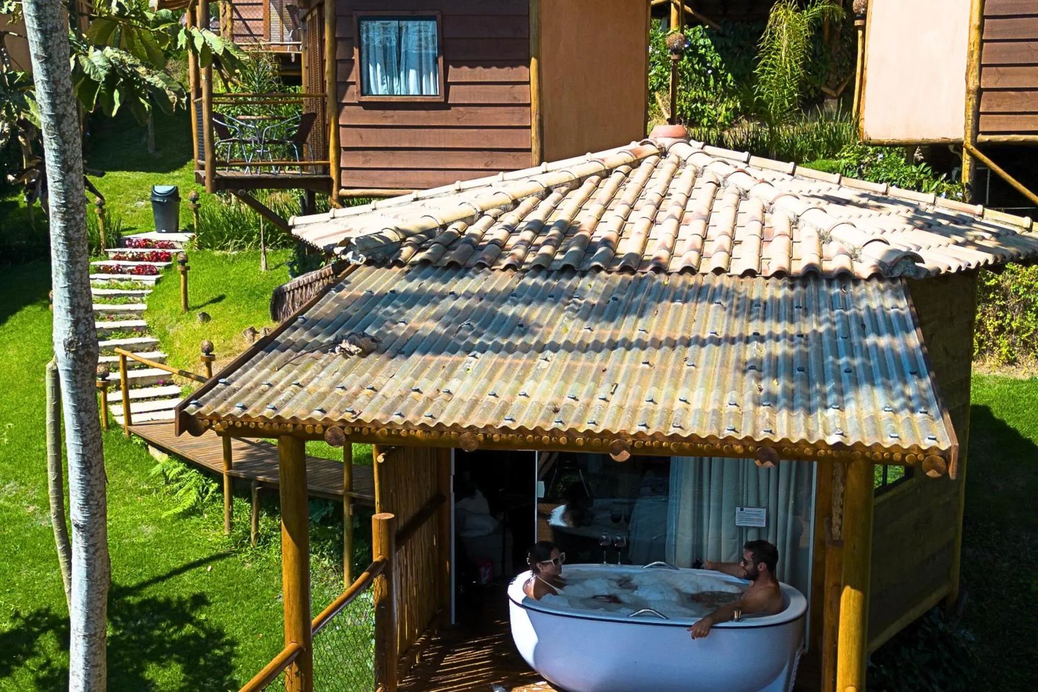 Deux hommes se détendent dans un bain à remous extérieur sur une terrasse en bois.
