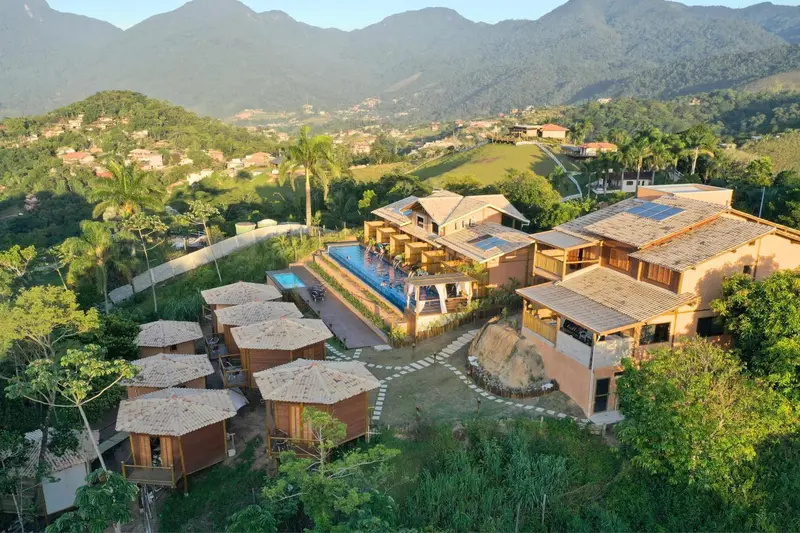 Vue aérienne d'un complexe hôtelier avec piscine et bungalows individuels au milieu d'une végétation luxuriante.