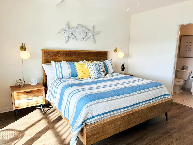 Une chambre lumineuse avec un grand lit recouvert d'une courtepointe rayée.