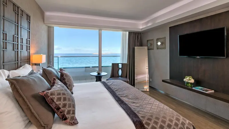 Chambre moderne avec un grand lit et vue sur la mer.