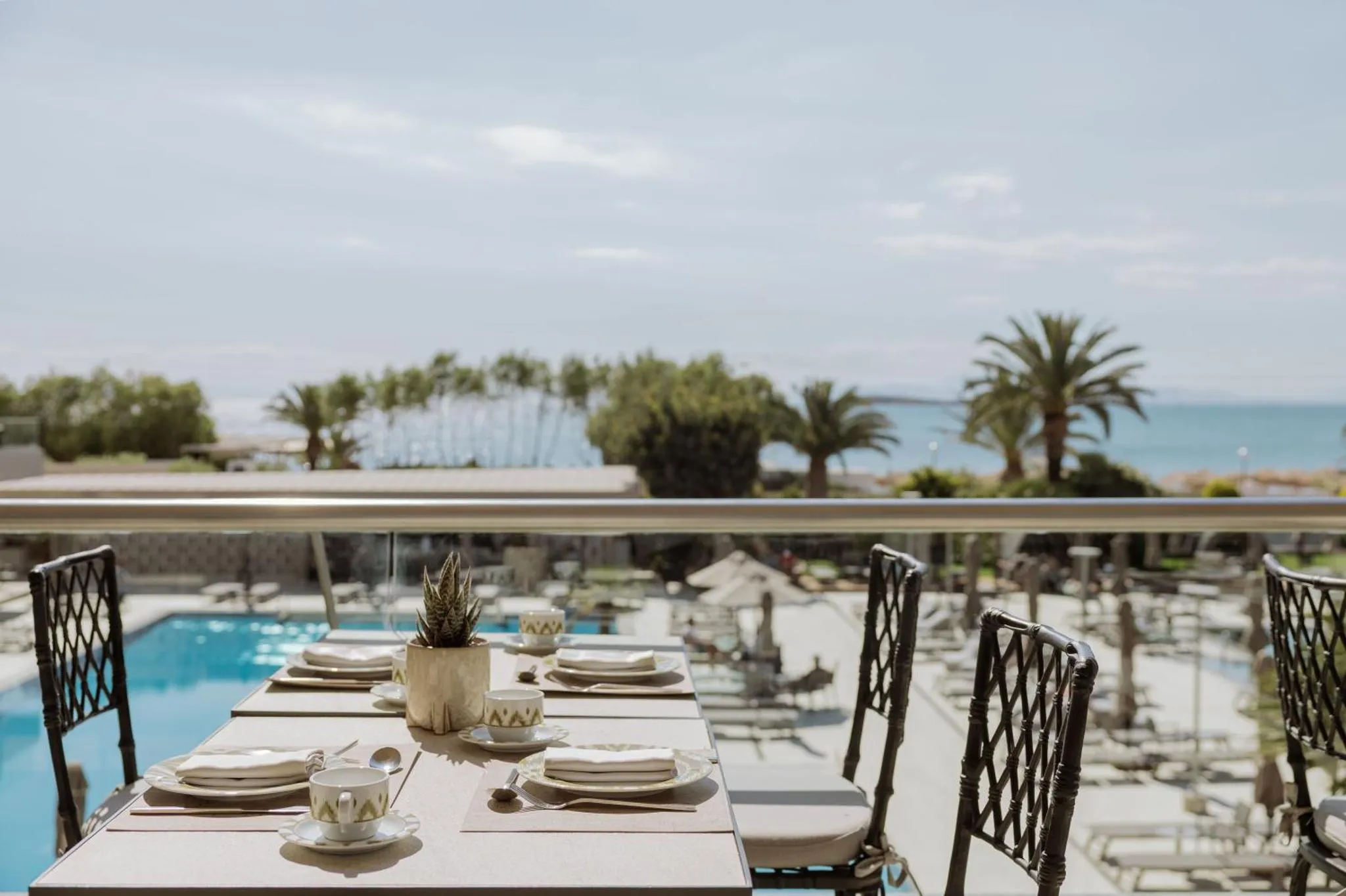Une table dressée en terrasse avec vue sur la mer et la piscine.