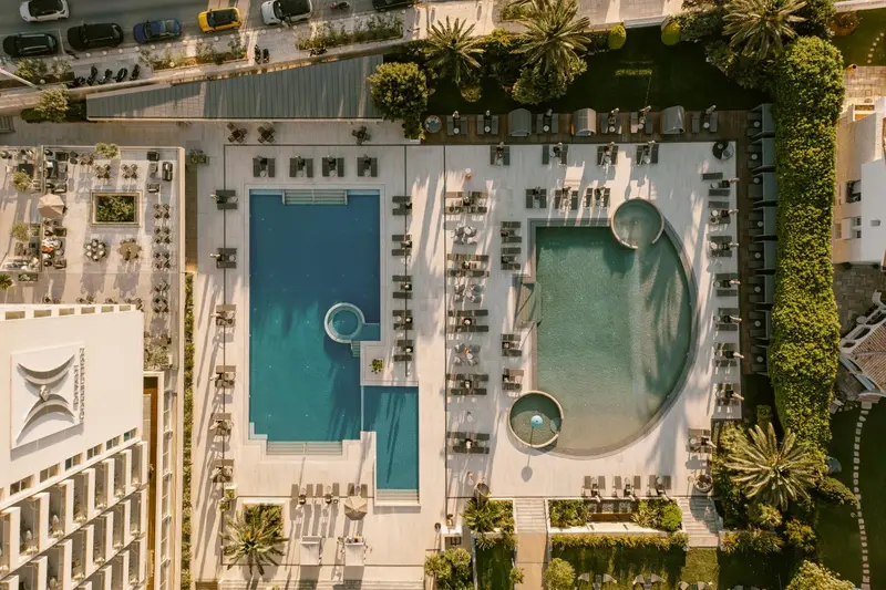 Vue aérienne d'un complexe hôtelier avec des piscines et des transats.