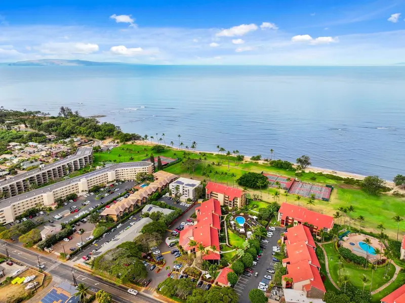 Vue aérienne d'un complexe hôtelier avec piscine et végétation luxuriante face à la mer.