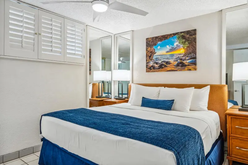 Une chambre lumineuse avec un grand lit recouvert d'une couverture bleue et de coussins.