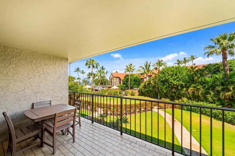 Terrasse carrelée avec table et chaises donnant sur un jardin tropical et la mer.