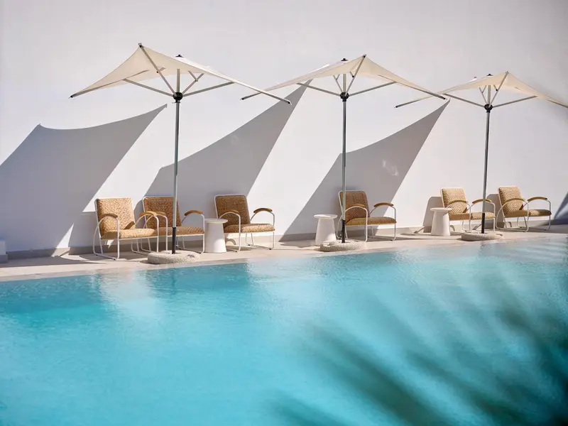Transats et parasols ombragent une piscine turquoise.