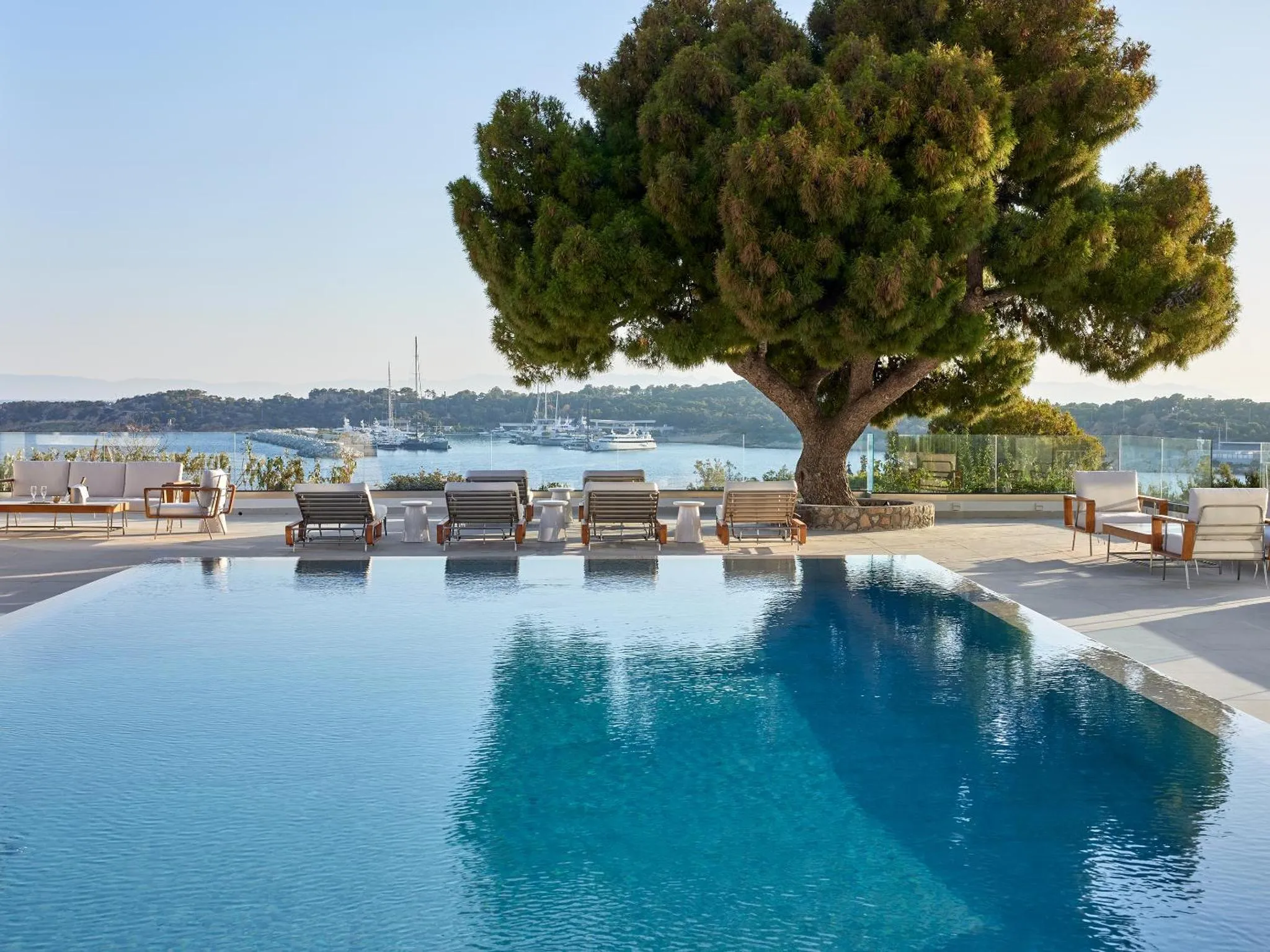 Une piscine à débordement offre une vue sur la mer et les bateaux amarrés.
