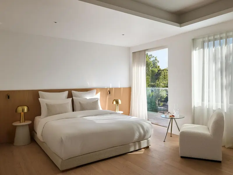 Une chambre lumineuse avec un grand lit et un fauteuil près d'une fenêtre.