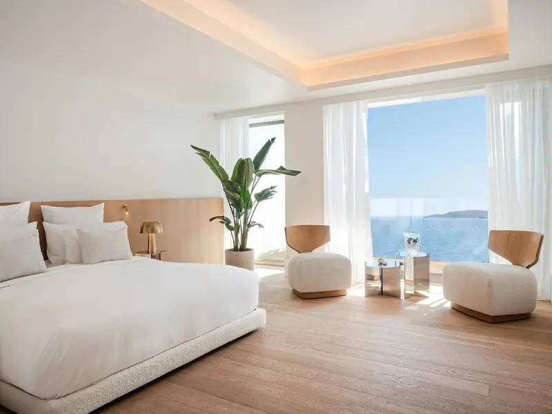 Chambre lumineuse avec un grand lit et une vue sur la mer.