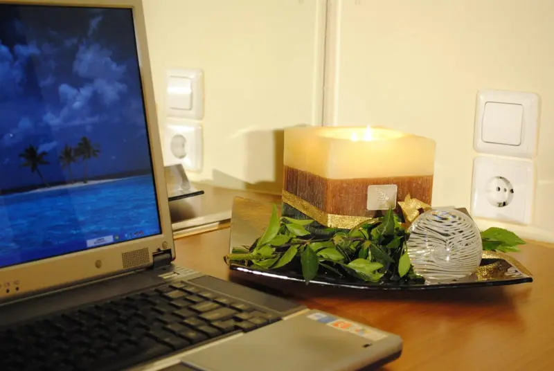 Une bougie décorative et un ordinateur portable sont posés sur une table en bois.