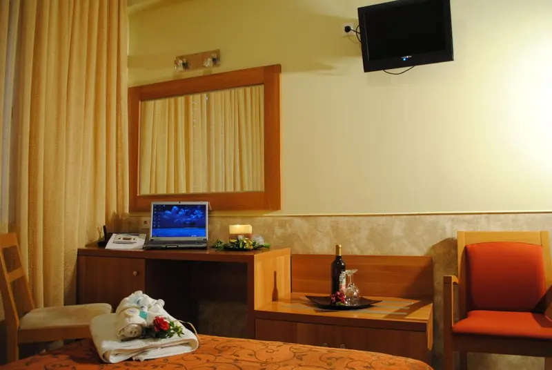 Une chambre d'hôtel lumineuse avec un bureau et une bouteille de vin.
