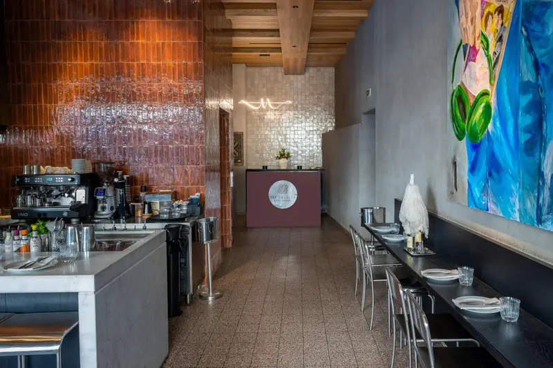 Un comptoir de bar et des tables sont disposés dans une salle lumineuse.