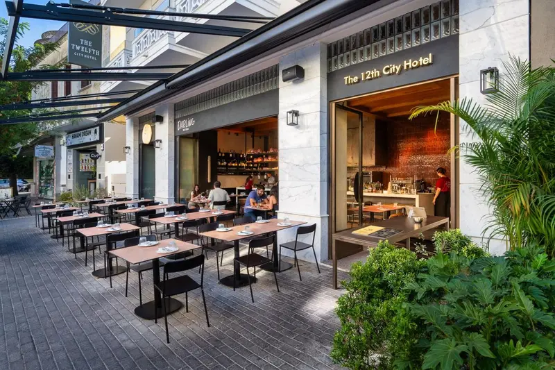 Terrasse de restaurant avec tables et chaises devant une façade d'hôtel.