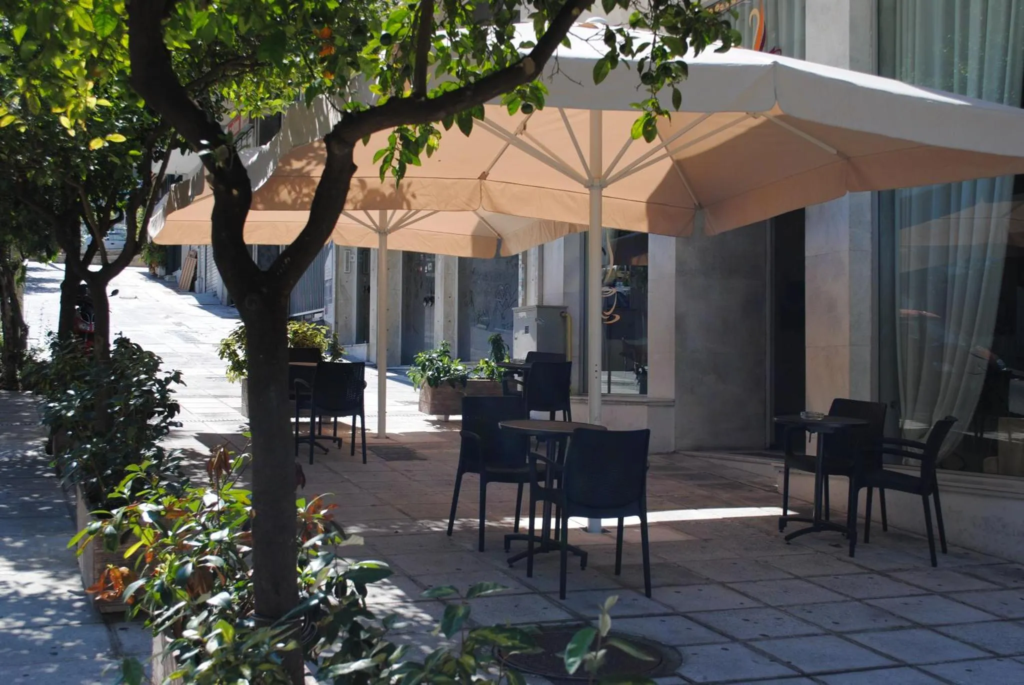 Terrasse ombragée avec tables et chaises en extérieur.