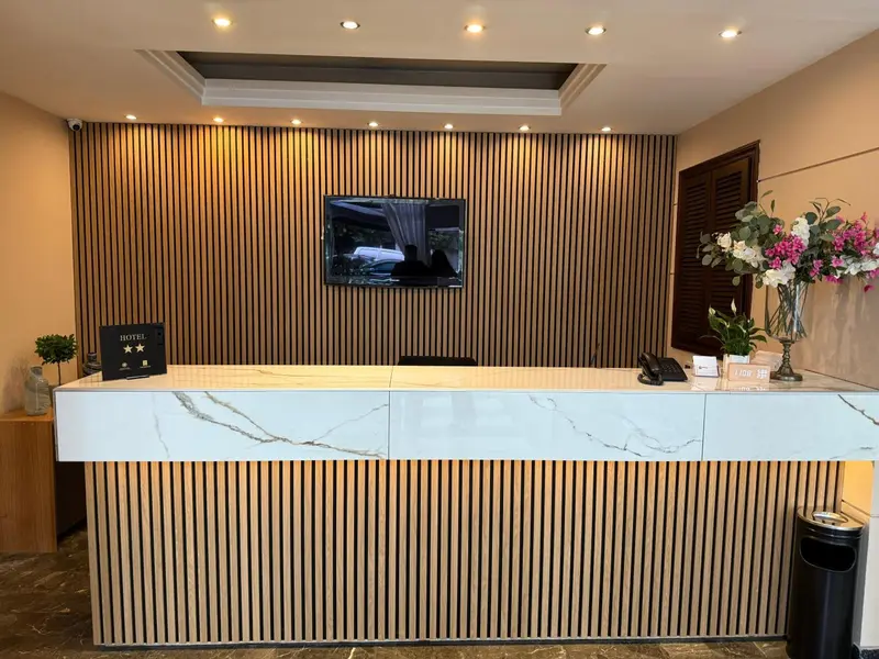 Un comptoir d'accueil moderne avec un mur décoratif en bois et des arrangements floraux.