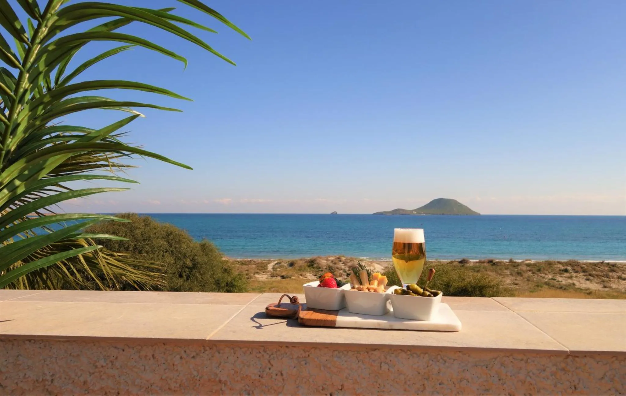 Une collation et une boisson rafraîchissante sont présentées sur une terrasse avec vue sur la mer.