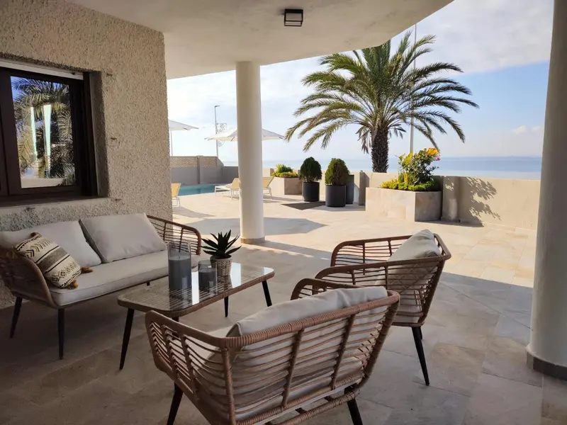 Espace de détente extérieur avec canapés et tables basses face à la mer.