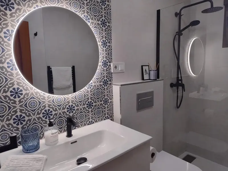 Une salle de bain moderne avec un grand miroir rond et une douche à l'italienne.