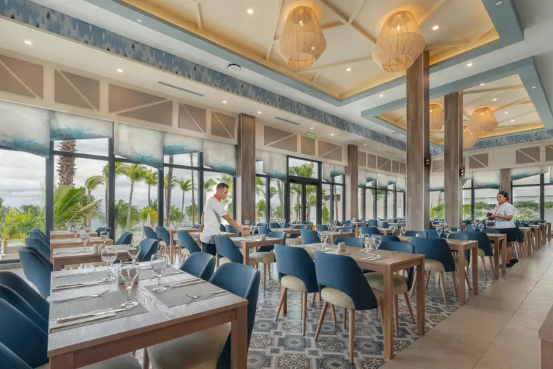 Une salle lumineuse avec des tables dressées pour le service.